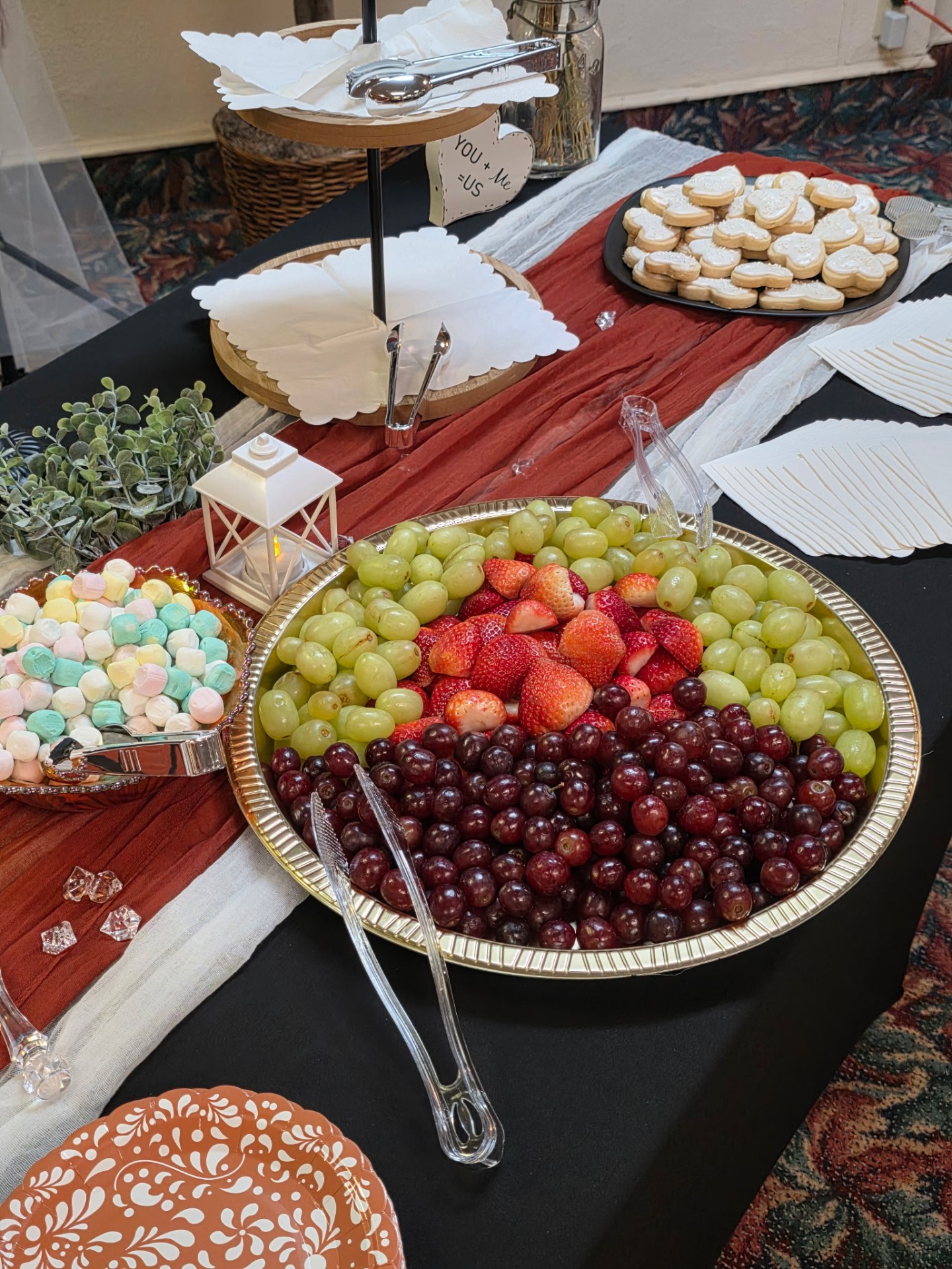Dessert and fruit grazing table with sugar cookies, marshmallows, grapes, and strawberries on a terracotta runner