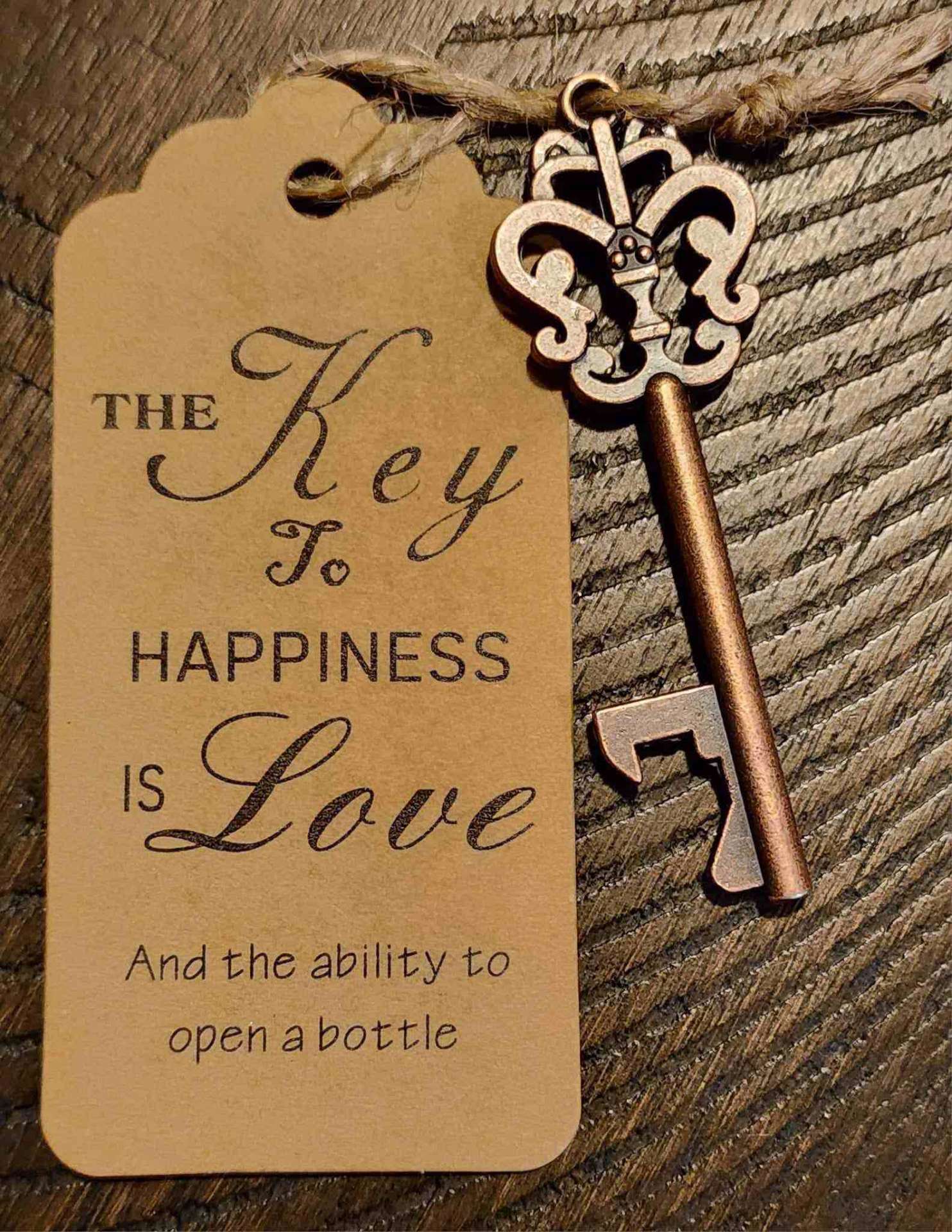 Vintage copper skeleton key bottle opener favor with a kraft tag reading 'The Key to Happiness is Love'