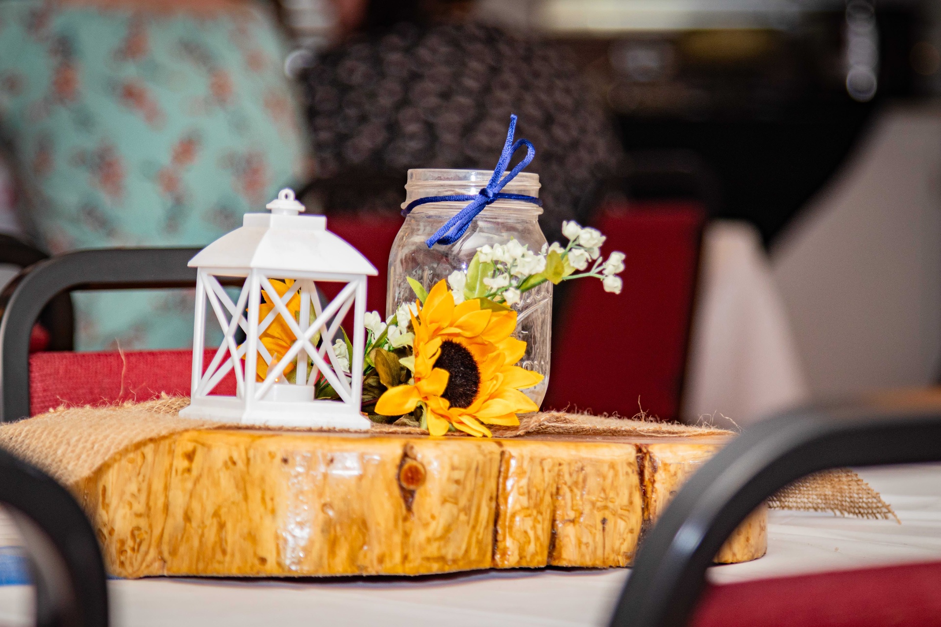 Sunflower and mason jar centerpiece on a polished wood slice with a white lantern